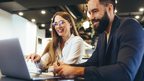 An image of a woman and man using a laptop and reviewing a document together